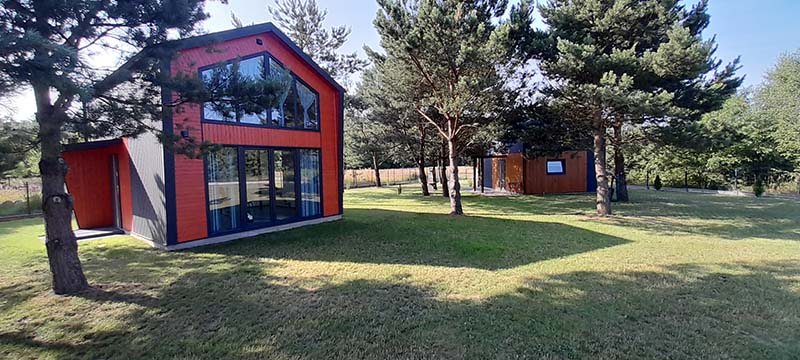 Niewielki dom z paneli SIP z przeszkloną ścianą szczytową — przykład zabudowy, nie konkretny model z katalogu